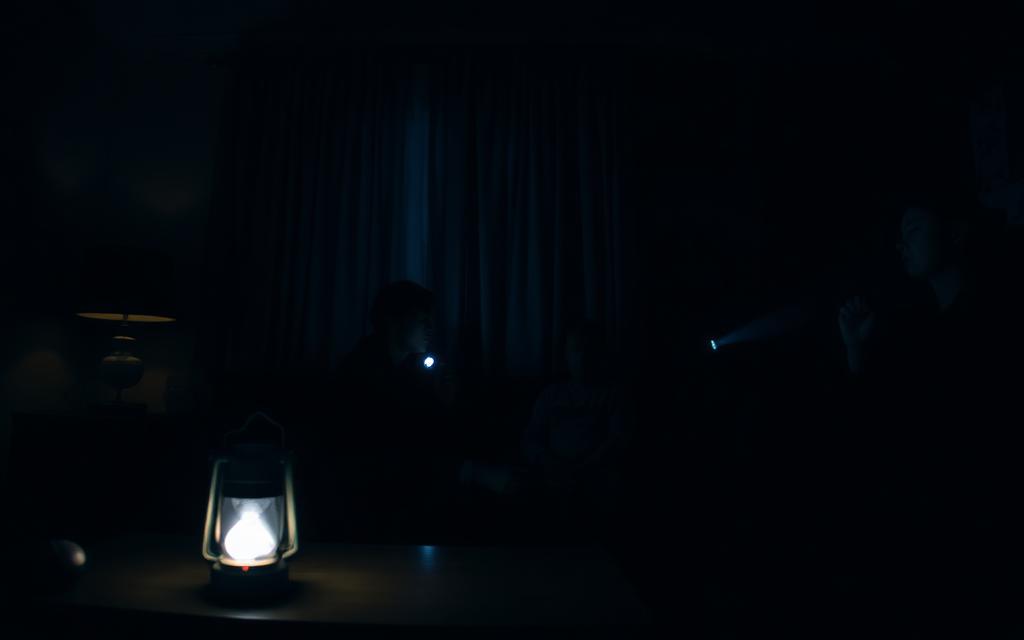 Donkere woonkamer tijdens stroomstoring met lantaarn en zaklamp